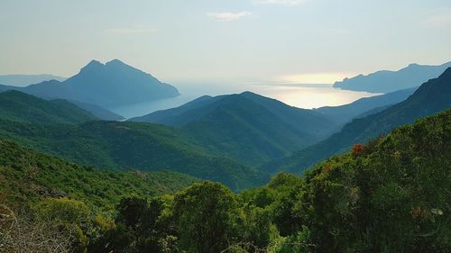 Scenic view of mountains and sea against sky during sunset