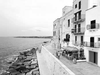 Buildings by sea against sky in city