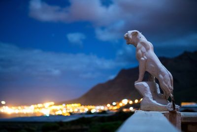 Statue against illuminated sea against sky