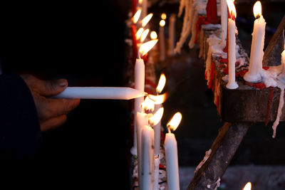 Midsection of man holding burning candles in temple