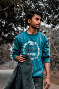 Man holding jacket while standing on footpath