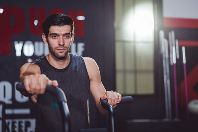 Portrait of young man exercising in gym