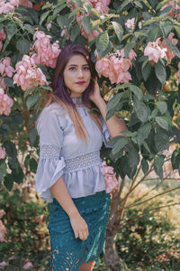 Portrait of beautiful young woman standing by flowering plants