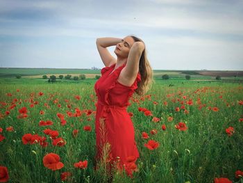 Young woman in red dress in a field of poppies