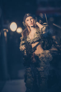 Portrait of young woman holding camera at night