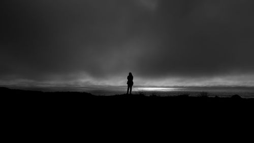 Silhouette man standing on beach against sky