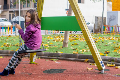 Portrait of girl sitting on swing at park