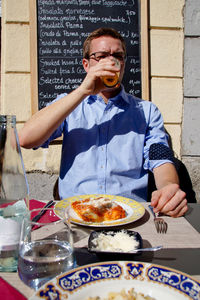 Man drinking alcohol while sitting on chair at restaurant