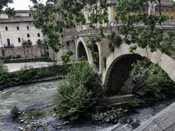 Arch bridge over river against buildings