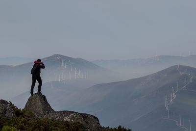 Man standing on rock against sky