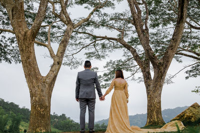 Rear view of couple standing against trees