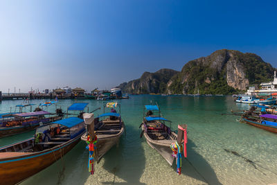 Boats moored on sea against blue sky