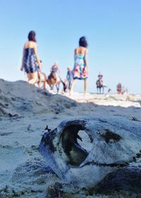 Low angle view of children on beach against clear blue sky