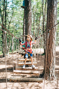 Boy riding bicycle on tree trunk in forest