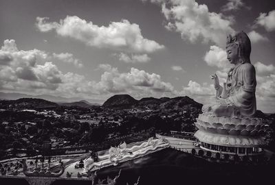 Statue by temple against building against sky