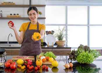 Young woman standing by fruits in kitchen at home