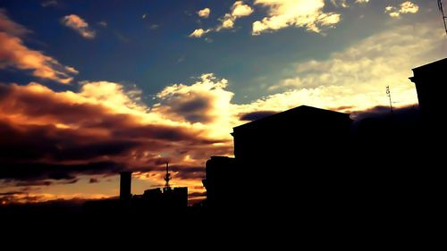 Silhouette of building against cloudy sky at sunset