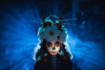 Portrait of person wearing mask against blue wall