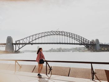 Woman standing on bridge against sky in city