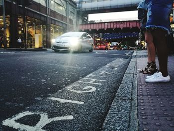 Low section of man standing on road in city