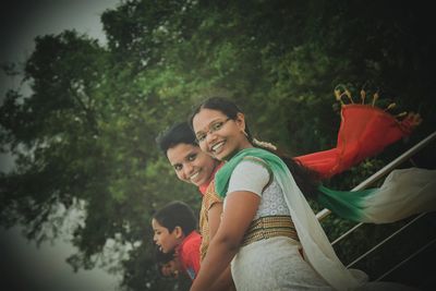 Rear view of mother and daughter on tree against plants