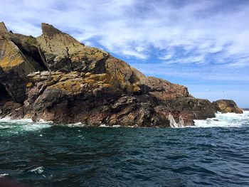 Rock formation by sea against sky