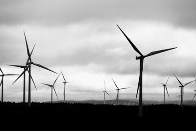 Wind turbines on field against sky