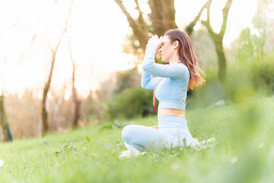 Full length of woman with arms raised on field