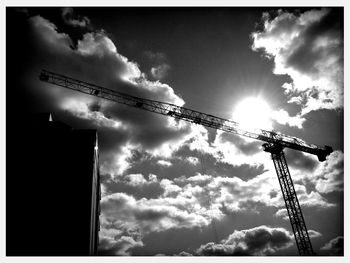 Low angle view of crane against cloudy sky