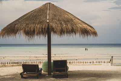 Lounge chairs on beach against sky