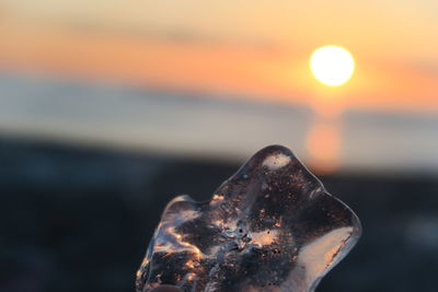 Close-up of rusty metal against sea during sunset