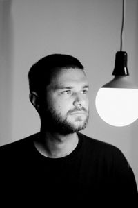 Mid adult man hanging against illuminated lamp at home