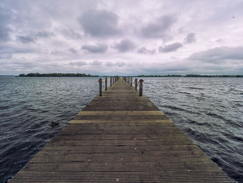 Wooden pier over sea against sky