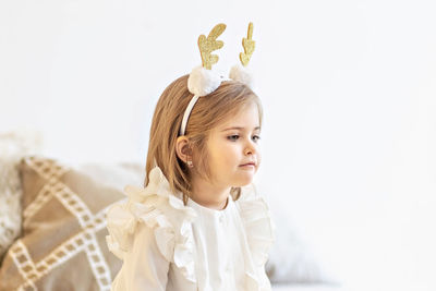 Portrait of a little girl toddler with a headband on her head  of deer horns. christmas holidays