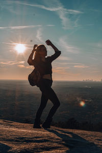 Full length of woman posing while standing on mountain against sky during sunset