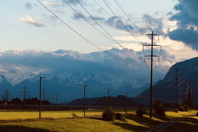 Electricity pylons on land against sky