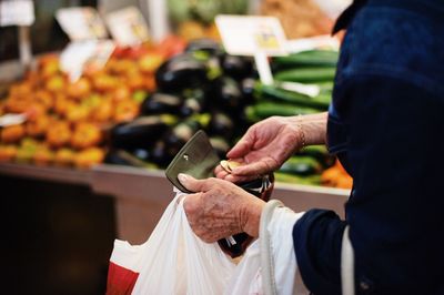 Midsection of woman buying vegetables at market