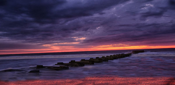 Scenic view of sea against dramatic sky during sunset