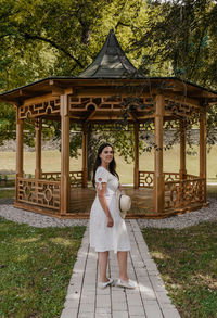 Full length of woman standing in front of pavilion in park