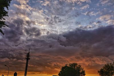 Low angle view of communications tower against cloudy sky