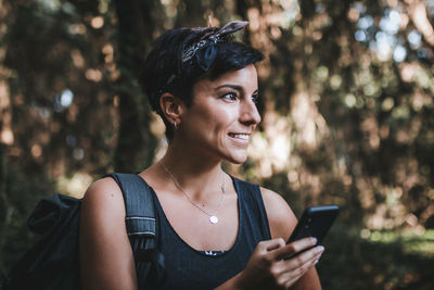 Portrait of smiling young woman using mobile phone outdoors