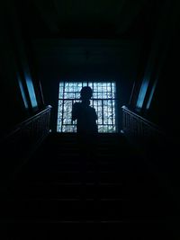 Low angle view of silhouette man standing on staircase in building