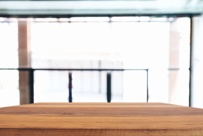 Close-up of wooden table against window at home