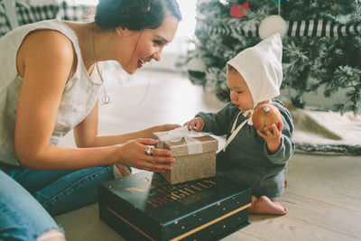 Mother showing christmas present white sitting at home