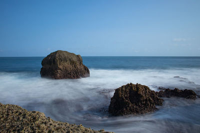 Scenic view of rocks in sea against sky