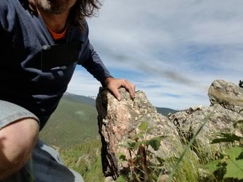 Midsection of man on rock against sky