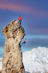 Man on rock against snowcapped mountains during winter