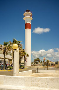 Lighthouse by building against sky