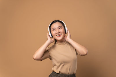 Portrait of young woman standing against yellow background