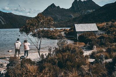 People standing by lake against mountain